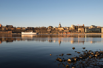 A sunny early spring day in Stockholm, view over a pier with boats and birds at the old town and the Södermalm district 