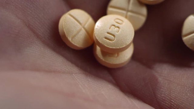 Macro close-up of amphetamine / dextroamphetamine pills dropping in a human hand