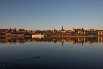 Fototapeta premium A sunny early spring day in Stockholm, view over a pier with boats and birds at the old town and the Södermalm district 