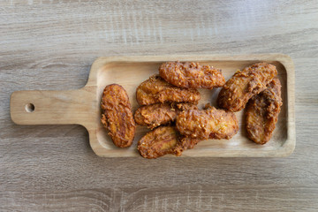 Deep fried banana in wooden dish on table.
