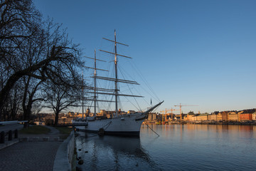 A sunny early spring day in Stockholm, view over a pier with boats and birds at the old town and the S&ouml;dermalm district 