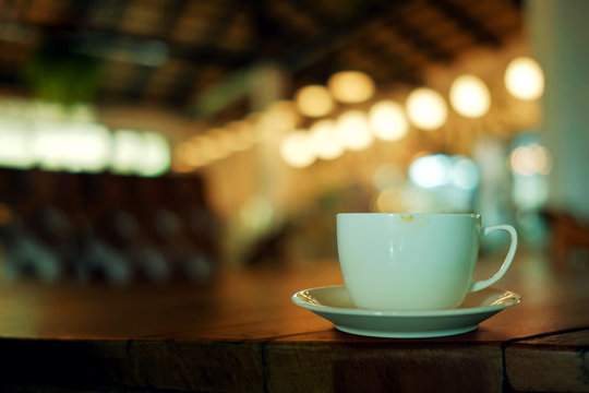 Coffee Cup on the Table in Cafe. Blurred Lights in bar as background