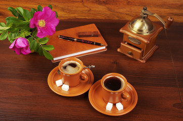 Morning coffee. A cup of coffee, coffee grinder, notebook, pen, rosehip flowers.