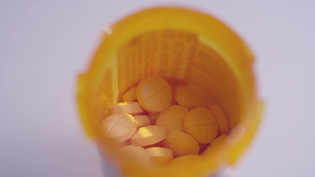 Macro close-up of a bottle full of amphetamine / dextroamphetamine pills spinning on a white surface