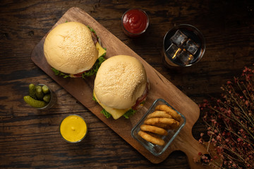 Homemade hamburger with tomato sauce, yellow mayonnaise and French fries on wooden table.