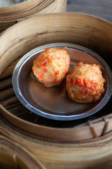 Dim sum stuffed shrimp or meat ball in tray on wooden table.