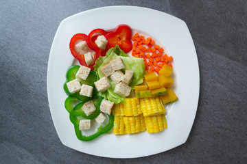 Healthy vegan,Salad with corn,pumpkin,carrot,bell pepper,lettuce and wheat bread in white dish on concrete table.