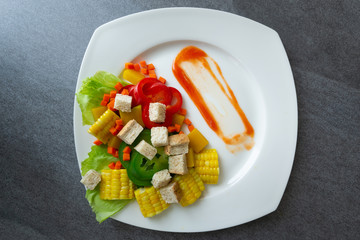 Healthy vegan,Salad with corn,pumpkin,carrot,bell pepper,lettuce and wheat bread in white dish on concrete table.