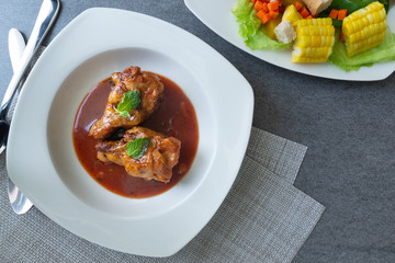 Spicy drumstick or Fried chicken with tomato sauce and black pepper in white dish on concrete table.