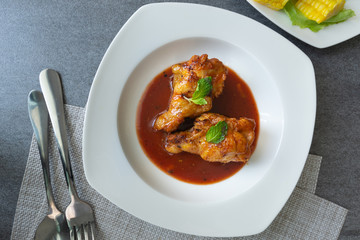 Spicy drumstick or Fried chicken with tomato sauce and black pepper in white dish on concrete table.