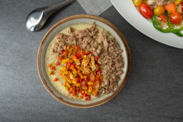 Beaten steamed egg with sweet pepper,carrot and chopped chicken in brown bowl on concrete table.