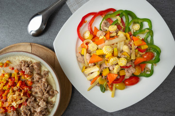 Stir fried vegetables with sweet pepper,tomato,pumpkin,corn and chicken in white dish on concrete table.