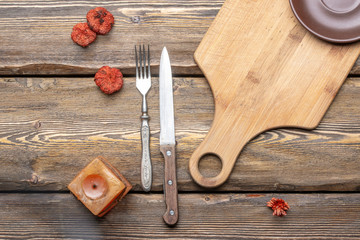 utensils with square candle and vintage cutlery on wooden background, top view 