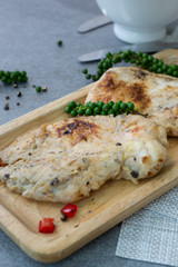 Fried chicken breast or chicken breast steak with black pepper in wooden dish on concrete table.