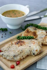 Fried chicken breast or chicken breast steak with black pepper in wooden dish on concrete table.