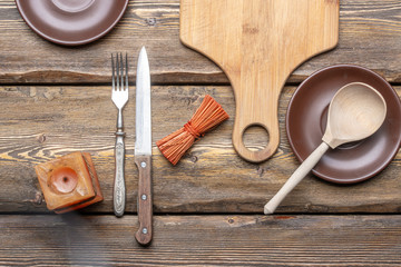 utensils with square candle and vintage cutlery on wooden background, top view 