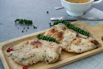 Fried chicken breast or chicken breast steak with black pepper in wooden dish on concrete table.