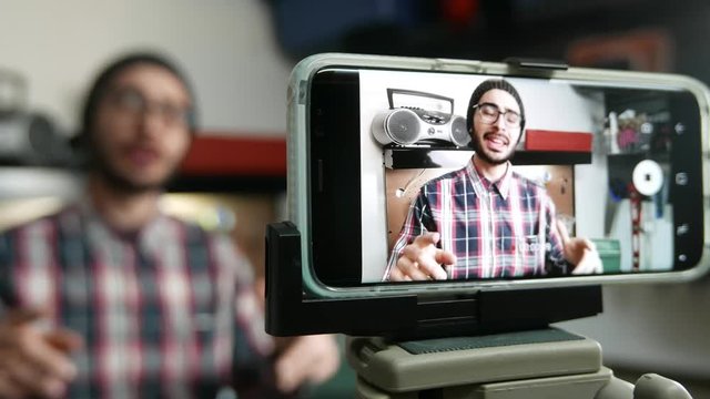 Millennial hipster vlogger filming a video of himself to post on social media.