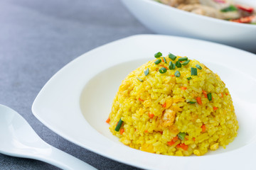 Fried rice with turmeric,carrot,egg and coriander or Yellow fried rice in white dish on concrete table.