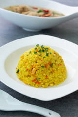 Fried rice with turmeric,carrot,egg and coriander or Yellow fried rice in white dish on concrete table.