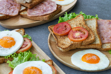 Fototapeta na wymiar Homemade sandwich or toast wheat bread with fried egg,lettuce,tomato in wooden table on the concrete table.