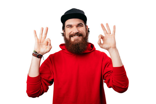 Portrait of handsome bearded guy in red hoody, showing that everthing it's ok
