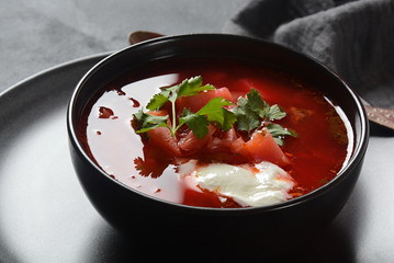 Traditional Ukrainian Russian borsch. Bowl of red beet root soup borsch with white cream on dark background. Beet Root delicious soup . Traditional Ukrainian food cuisine