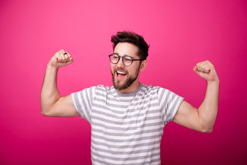 Protrait of happy young man in glasses, doping winner gesture with arms up