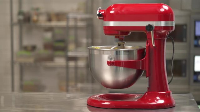 Demonstration video of a professional electronic mixer blending ingredients into dough. Blurred background. Bakery production concept