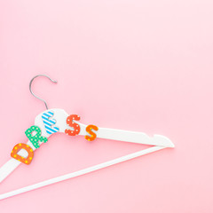 White hangers with dress text on pink background