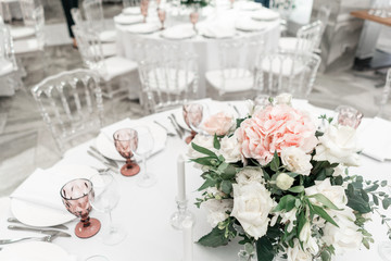 Flower arrangement in the center of the table. Interior of restaurant for wedding dinner, ready for guests. Round Banquet table served. Catering concept.