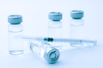 Vaccines, botulinum toxin and insulin ampules concept theme with glass vials with clear liquid next to a syringe and a hypodermic needle isolated on white background