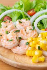 Shrimp salad with corn,green oak, onion and tomato in wooden dish.