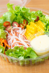 Crab sticks salad with corn,green oak, onion and tomato in clean plastic box.