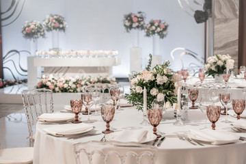 Round Banquet table served. Interior of restaurant for wedding dinner, ready for guests. Decorated with floral arrangement. Dishes, wine glasses and napkins. Catering concept.