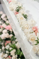 Small flower arrangements in ball glass vases. The table of the newlyweds. Interior of restaurant for wedding dinner, ready for guests. Catering concept.