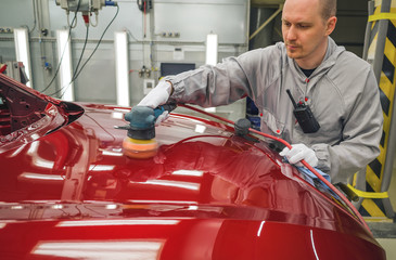 Fototapeta premium Employee in the shop painting the car body polishes painted body parts