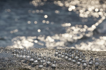 Chess pieces on a natural chessboard with glitter blur sea in background