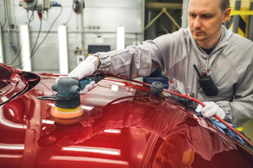 Fototapeta premium Employee in the shop painting the car body polishes painted body parts
