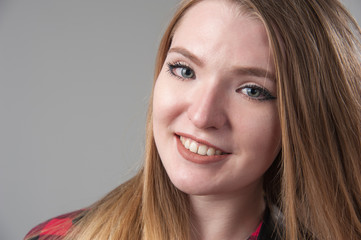 Portrait of a young attractive woman with blond hair on a neutral gray background.