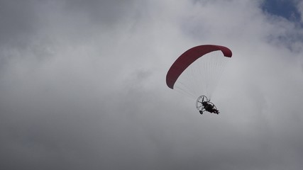 Parachute with motor flying on dark cloudy sky, dangerous flight