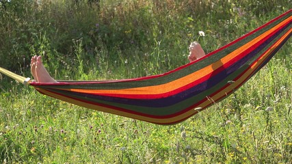 Girl relaxing in hammock, playing a daisy flower in the hands