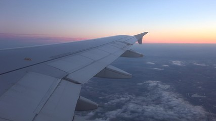 Fototapeta na wymiar Airplane wing seen on window and sunset red sky