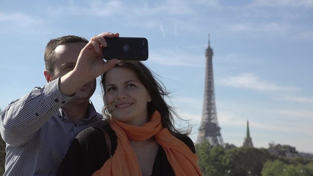 Portrait of happy couple making selfie, Eiffel tower in background, man and woman smiling, sweet tenderness,