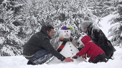 Fototapeta na wymiar Beautiful family building together a snowman