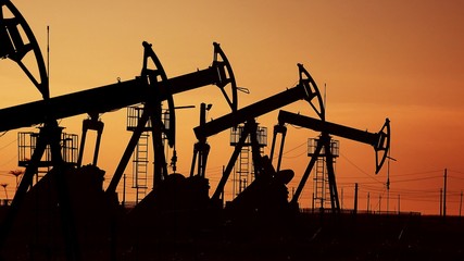 Many oil pumps at sunset under the red sky on industrial platform field with crude petroleum...