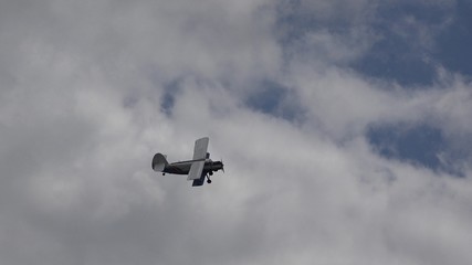 Airplane with propeller fly on blue sky with fluffy clouds, unsafe flight, airshow