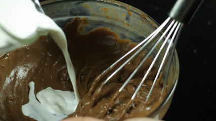 Fototapeta premium Close-up of melted chocolate blended with whisk on cream