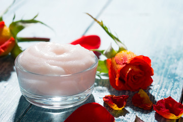 beauty products with rose flowers and petals on blue wooden table background
