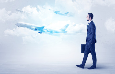 Obraz premium Elegant businessman going somewhere with briefcase and airplane on the background 